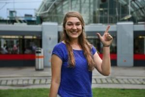 Photo of student showing cowboy sign while looking at the camera.